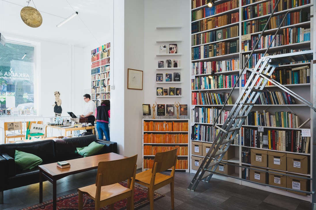 Arkadia International bookshop interior with floor-to-ceiling shelves, armchairs, and a library ladder in Helsinki.