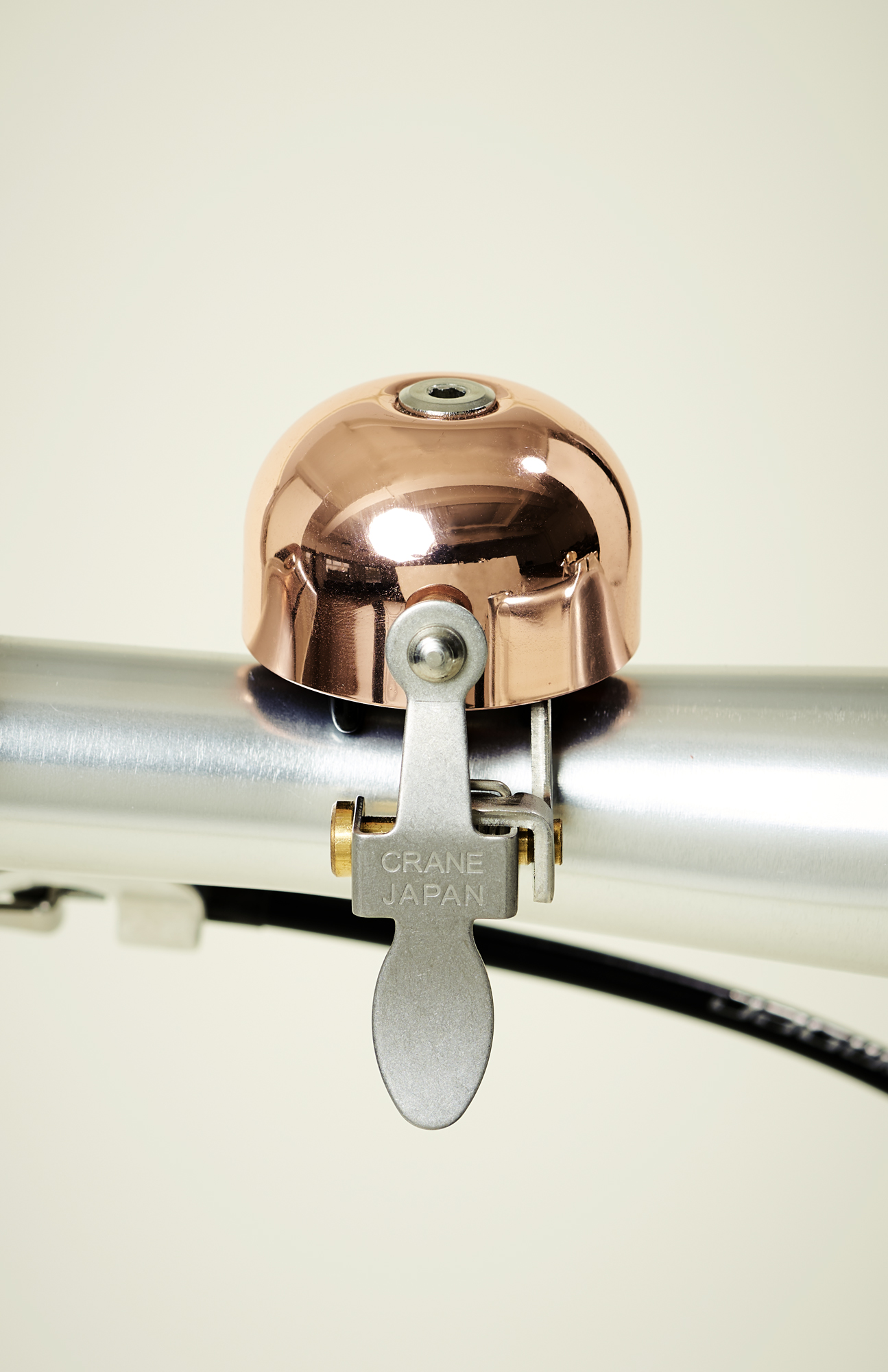 Crane Bell Co copper-colored bicycle bell mounted on handlebars with silver lever mechanism.
