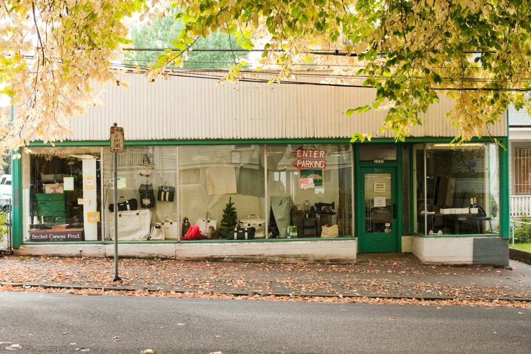 Beckel Canvas storefront in Portland with green trim, displaying tents and bags in windows.