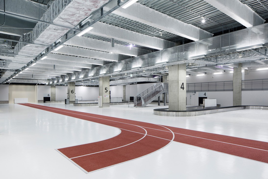 Interior of Narita Terminal 3 with two-toned running track floor and minimalist design guiding travelers to gates.