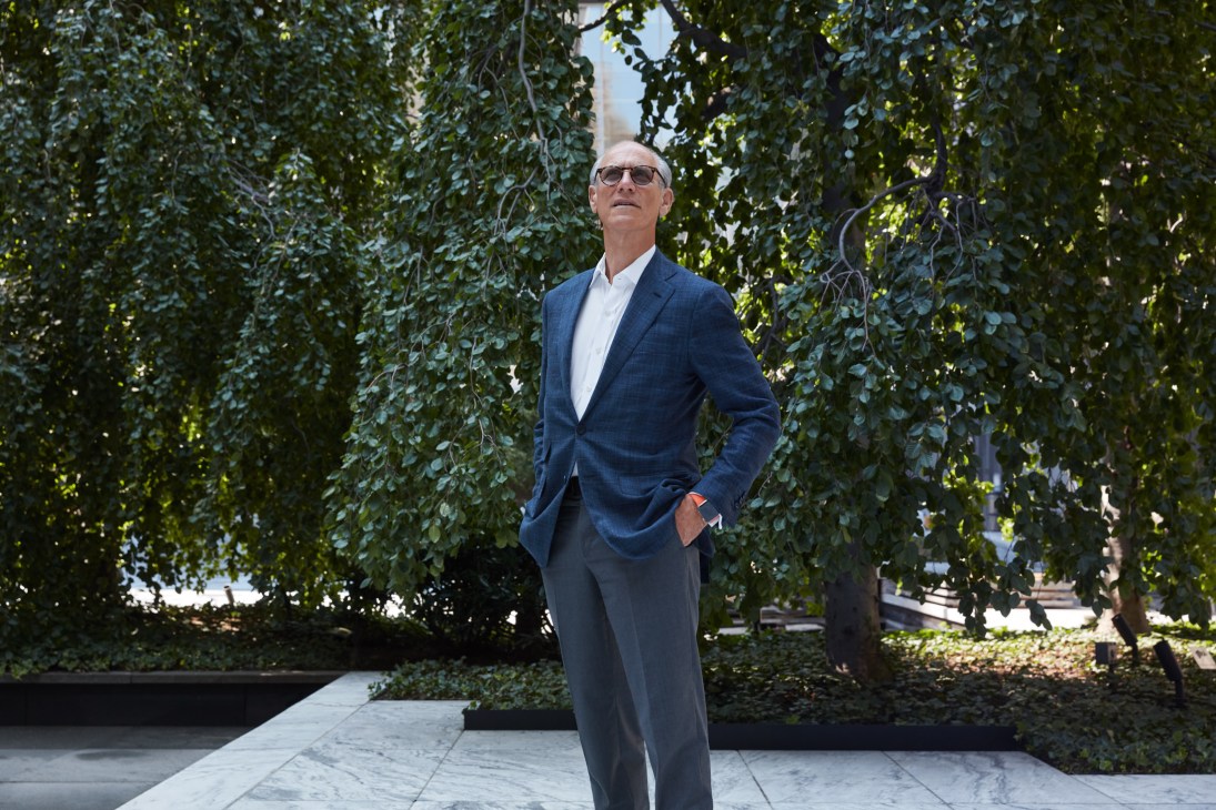 Glenn Lowry, director of the Museum of Modern Art in New York, stands in an ivy-covered courtyard wearing a navy blazer and glasses.