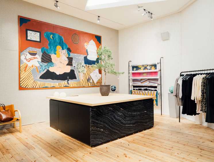 Samuji flagship store interior with colorful abstract painting, black counter, and clothing racks.