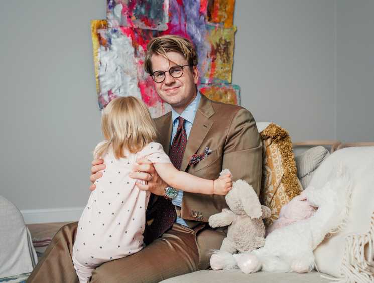 Niclas Ahlström, founder of Made by Choice, sits on a couch with a young child and stuffed toys, with colorful artwork on the wall behind.