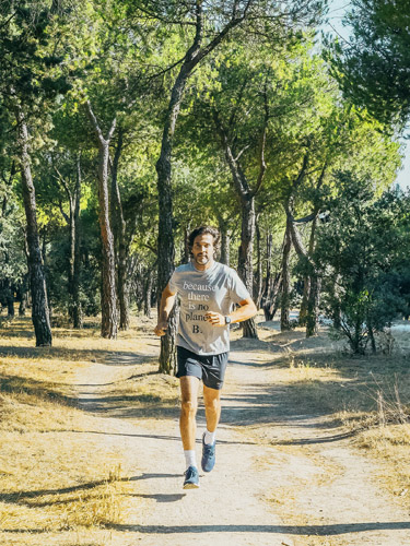 Man jogging on a tree-lined park path wearing athletic attire.