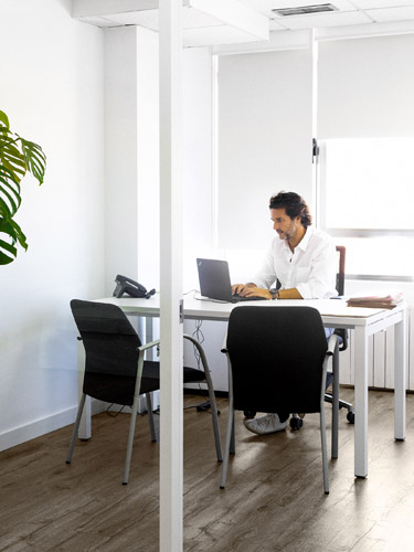 Javier Goyeneche working at his desk in an open office with an empty chair across from him.
