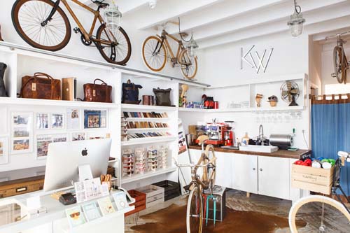 Interior of In Bed retail shop in Sydney with white shelving, hanging bicycles, and workspace.