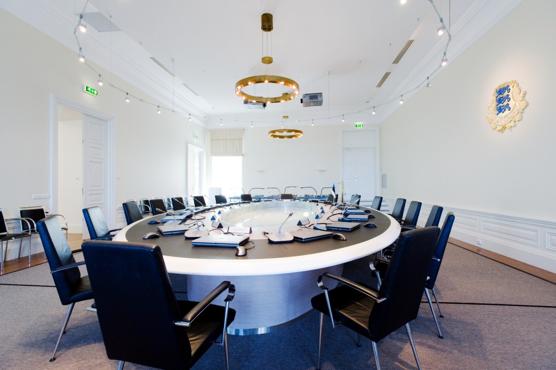 Modern paperless cabinet meeting room with oval table, blue chairs, and brass pendant lights at Stenbock House in Tallinn.