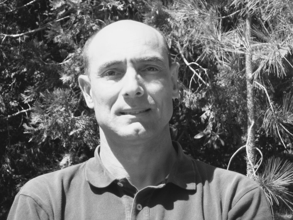 Black and white portrait of Khalid Benhamou, director of Sahara Wind, outdoors with foliage background.