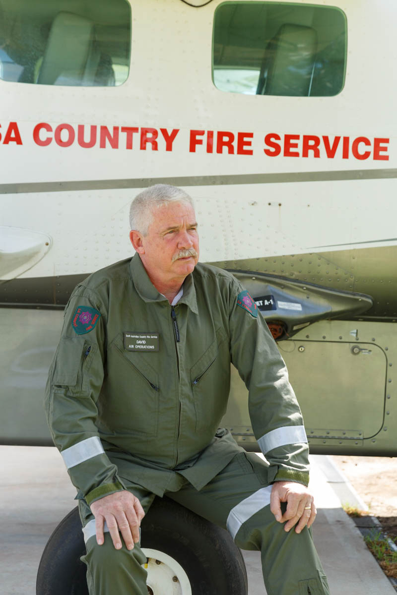 Commander David Pearce in flight suit sitting in front of a South Australian Country Fire Service aircraft.