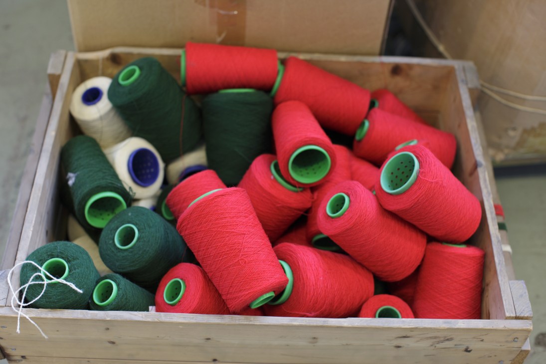 Spools of red and green Norwegian lambswool yarn in a wooden box at Røros-Tweed.