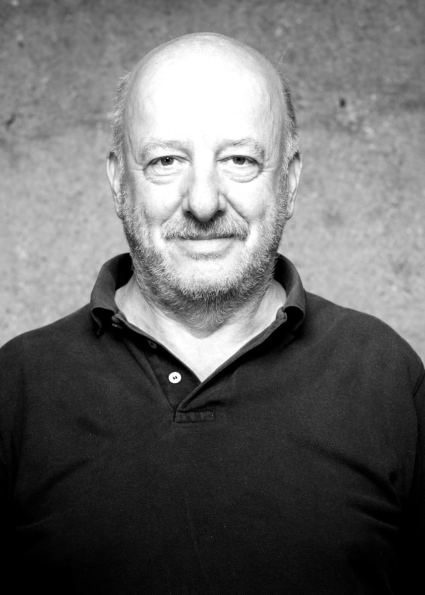 Black and white portrait of George Beylerian, a middle-aged man with white hair and beard wearing a black polo shirt.