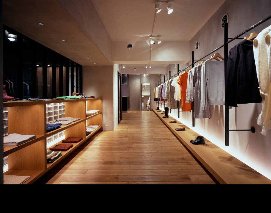 Minimalist retail interior with wooden fixtures, clothing racks, and neutral lighting in a modern boutique.