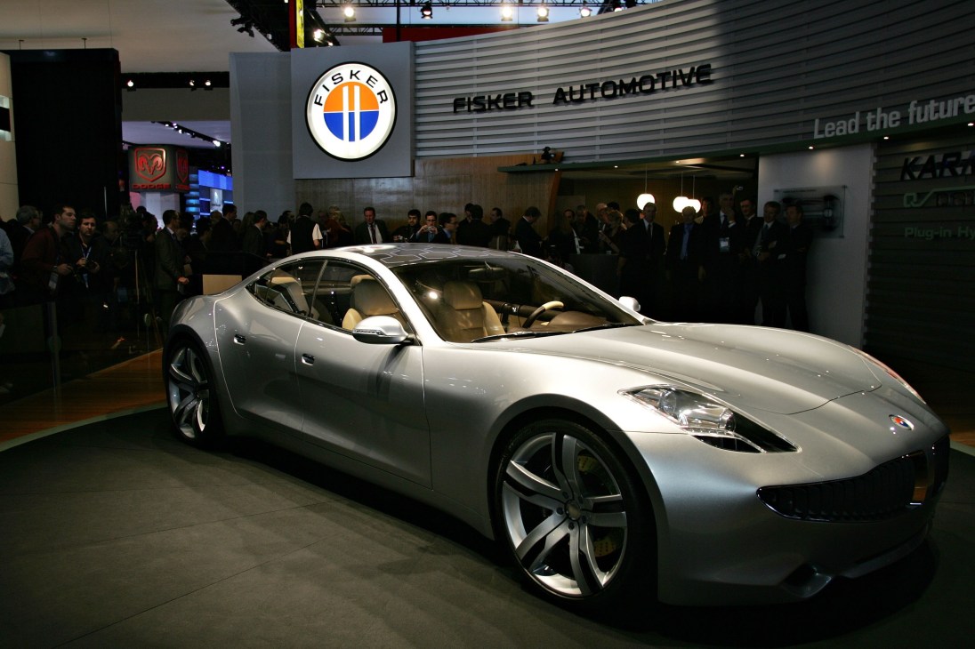 Silver Fisker Karma hybrid car on display at automotive show with Fisker Automotive branding visible.