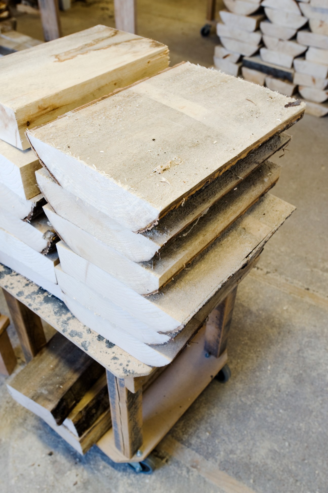 Stacked wooden clog soles with white rubber bases at various stages of production in the Talla workshop.