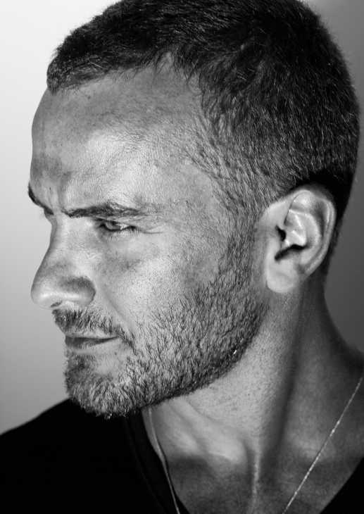 Black and white portrait photograph of a man in profile, wearing a dark t-shirt.