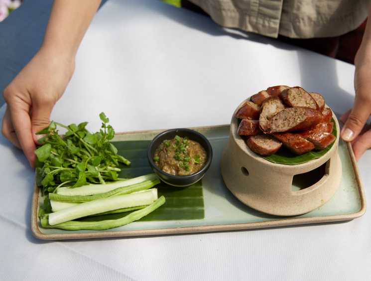 Laotian sausage dish served with fresh herbs and dipping sauce at Manda de Laos restaurant.