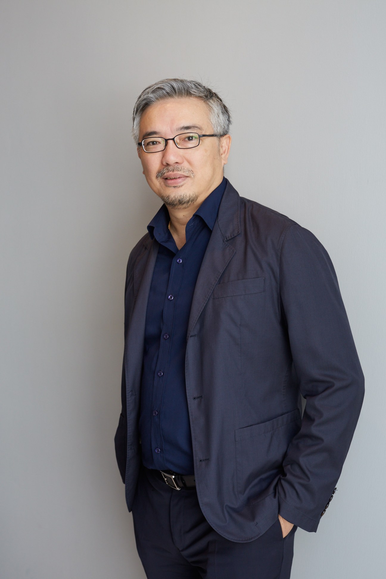 Professional headshot of Tos Chirathivat, CEO of Central Group, wearing glasses and a dark navy blazer