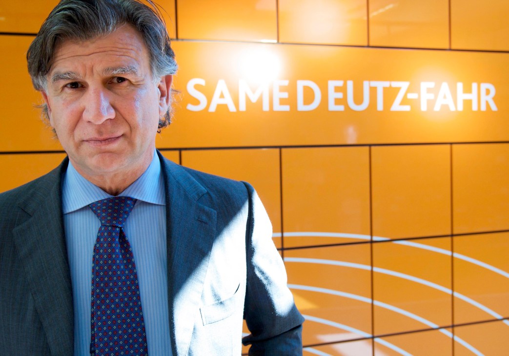 Man in business suit standing before Same Deutz-Fahr branded orange wall.