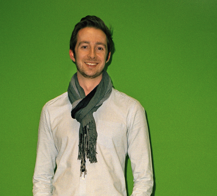 Alex Morgan, presenter of The Cube, smiles at the camera against a green background.