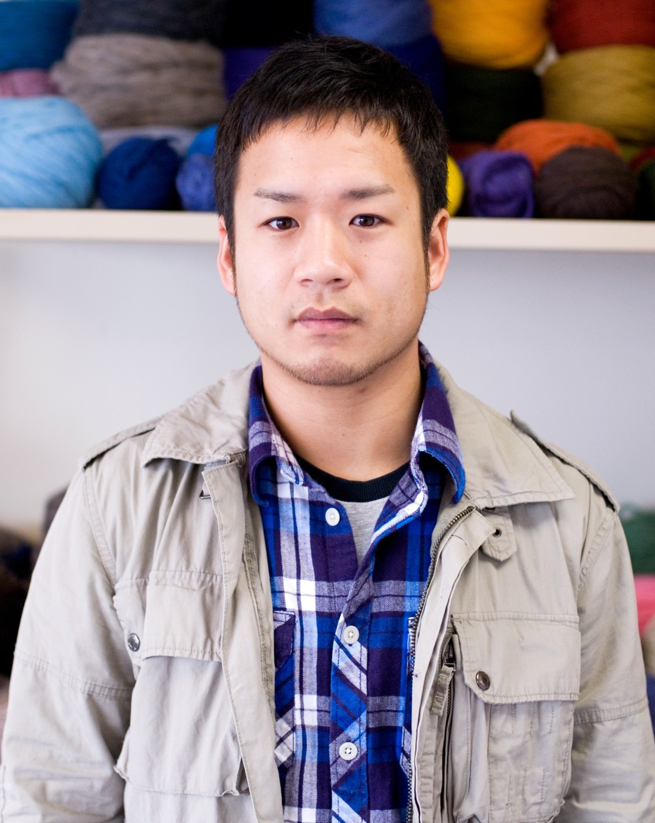 Minoru Hirano, creative director at Granted, stands in front of colorful yarn balls in a knitting workshop.