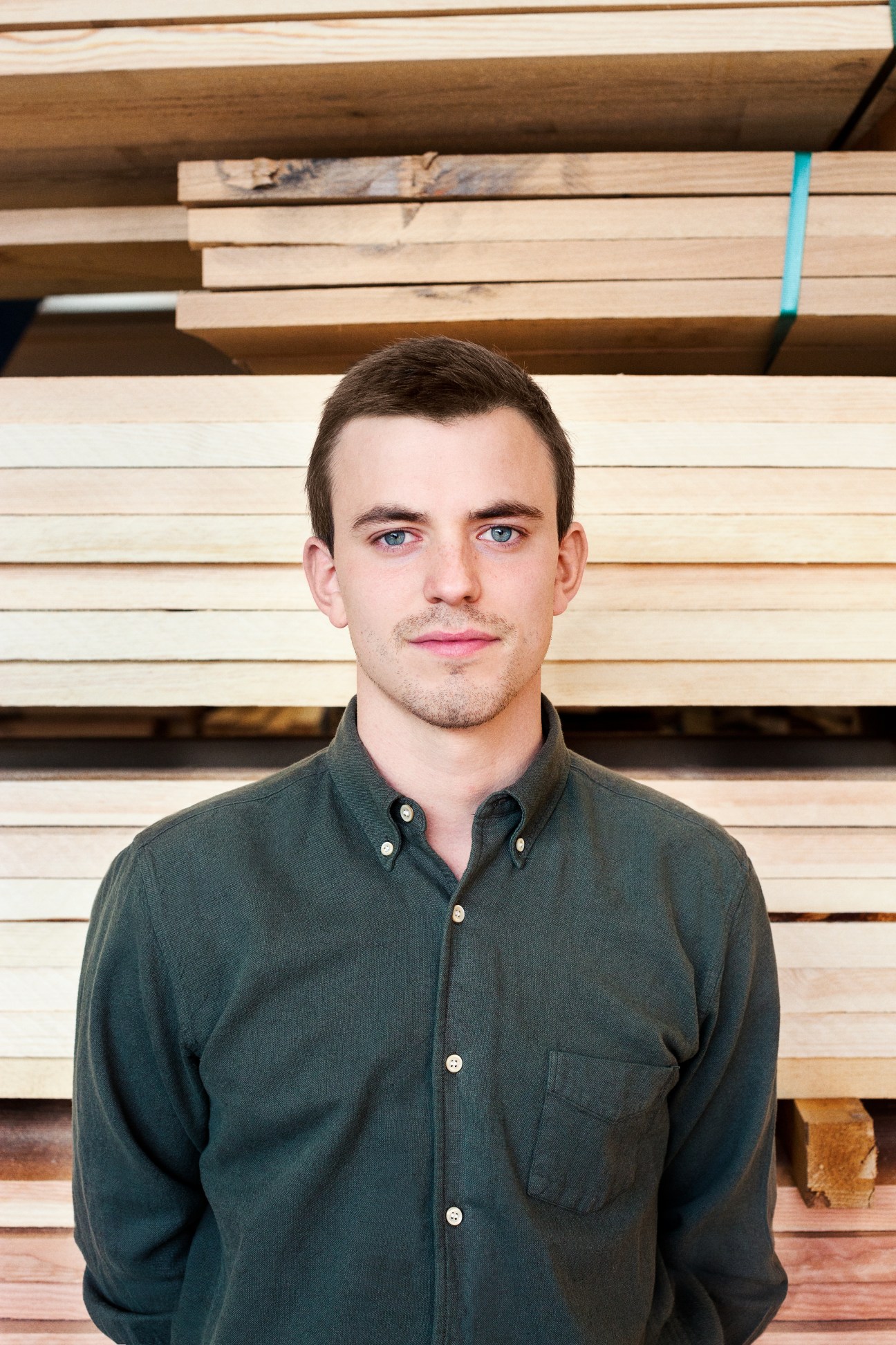 Hans Peter Dinesen poses for a portrait in front of stacked wooden planks.