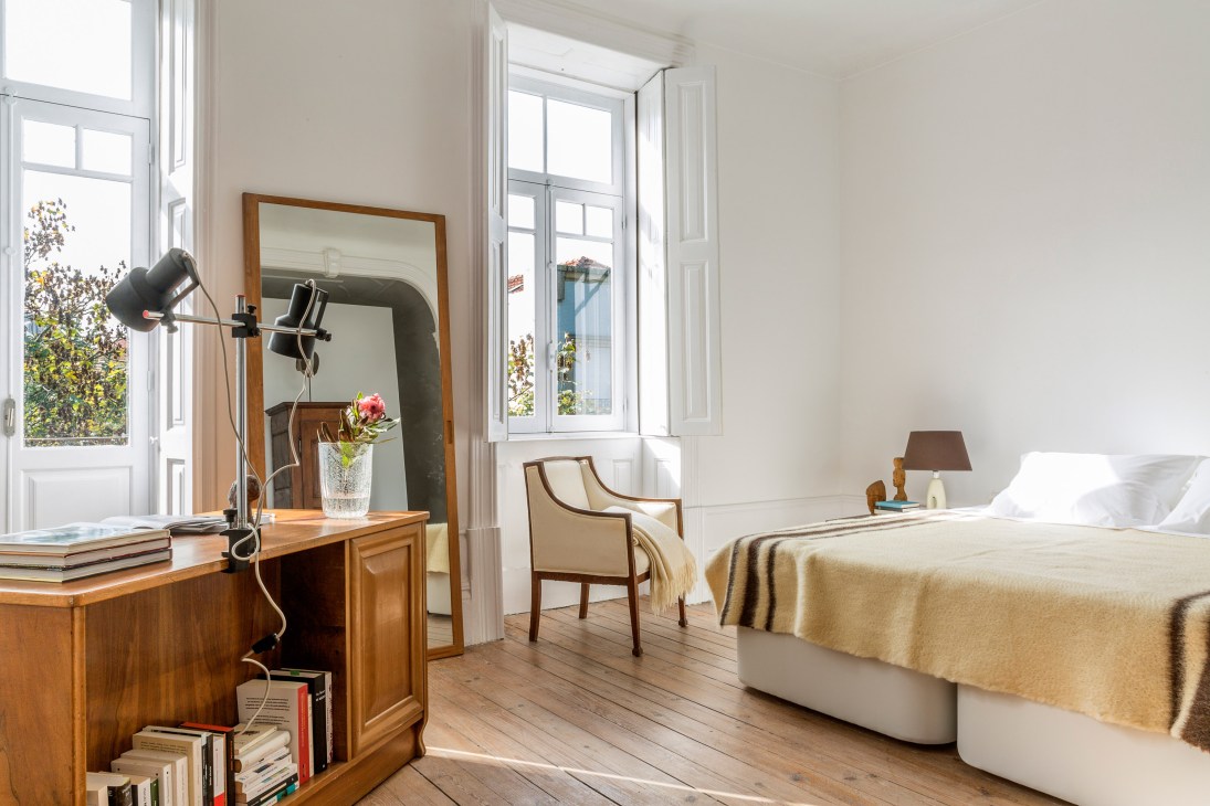 Bright bedroom with wooden desk, mirror, mid-century chair and bed at Refuge du Montenvers in Chamonix.