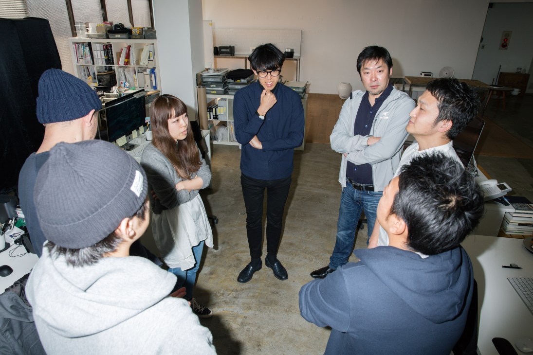 Gen Terao leads a brain-training word game with his Balmuda design team in an office space.