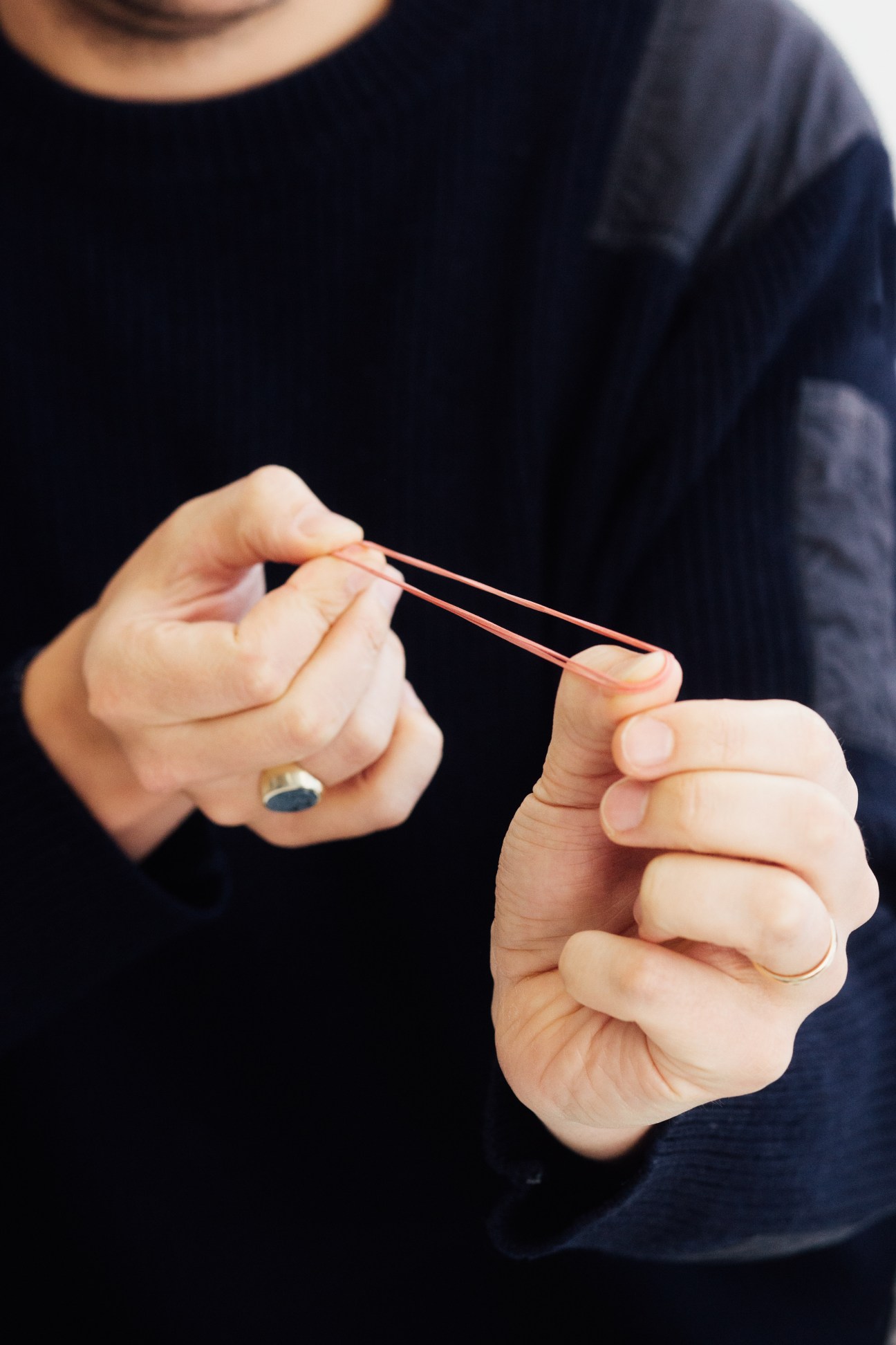 Person holding a red rubber band stretched between their hands.