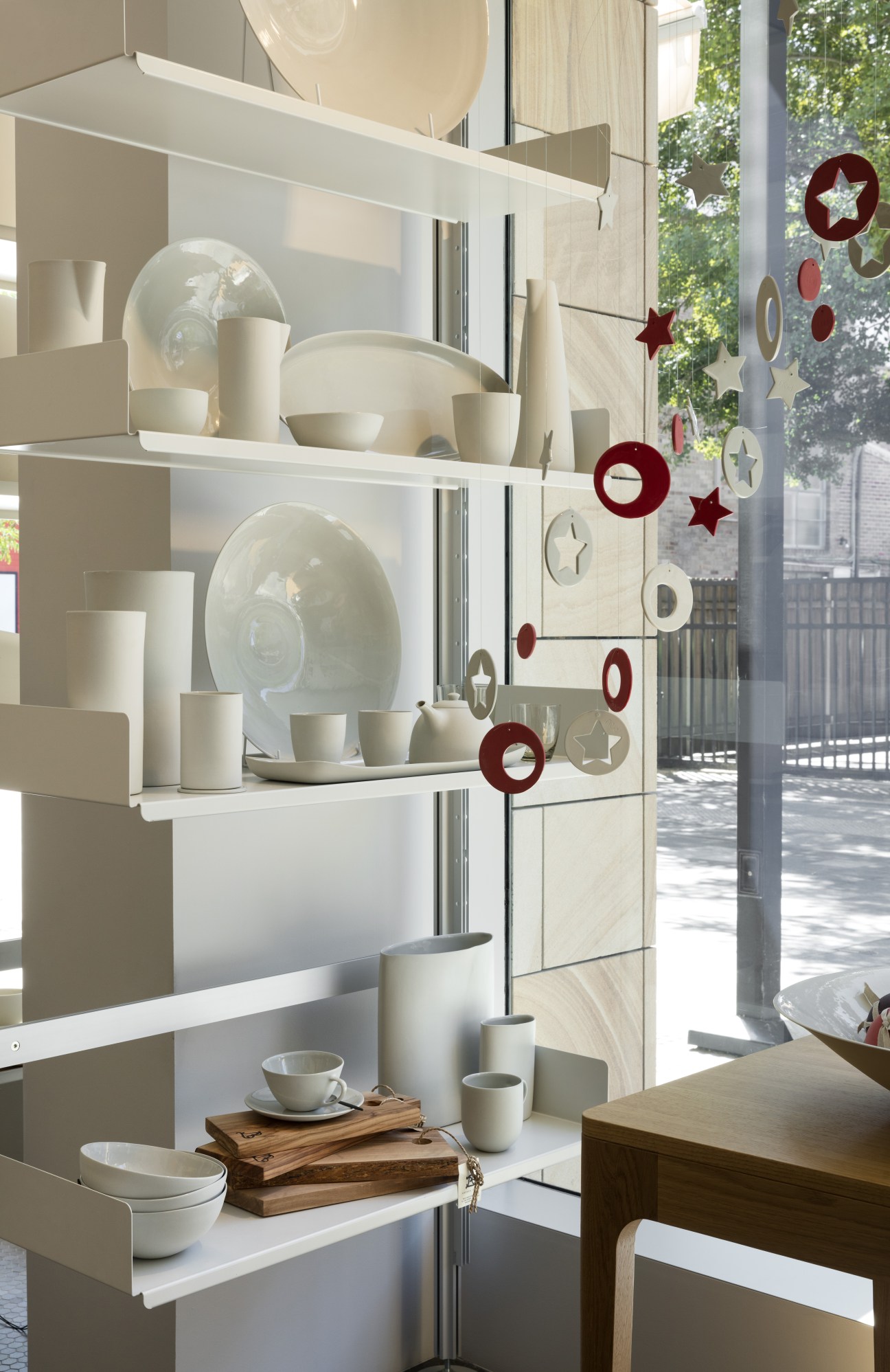 Mud Australia's café-shop interior displaying handcrafted porcelain tableware in neutral tones on white shelving with festive decorations.