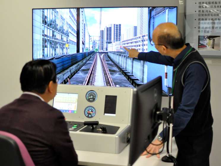 Two people using an MTR train simulator at the operator's training academy in Hung Hom, Hong Kong.