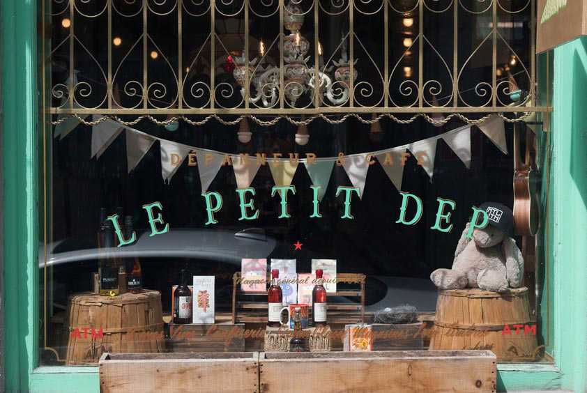Le Petit Dépanneur storefront with turquoise frame, ornate window grille, and curated window display.