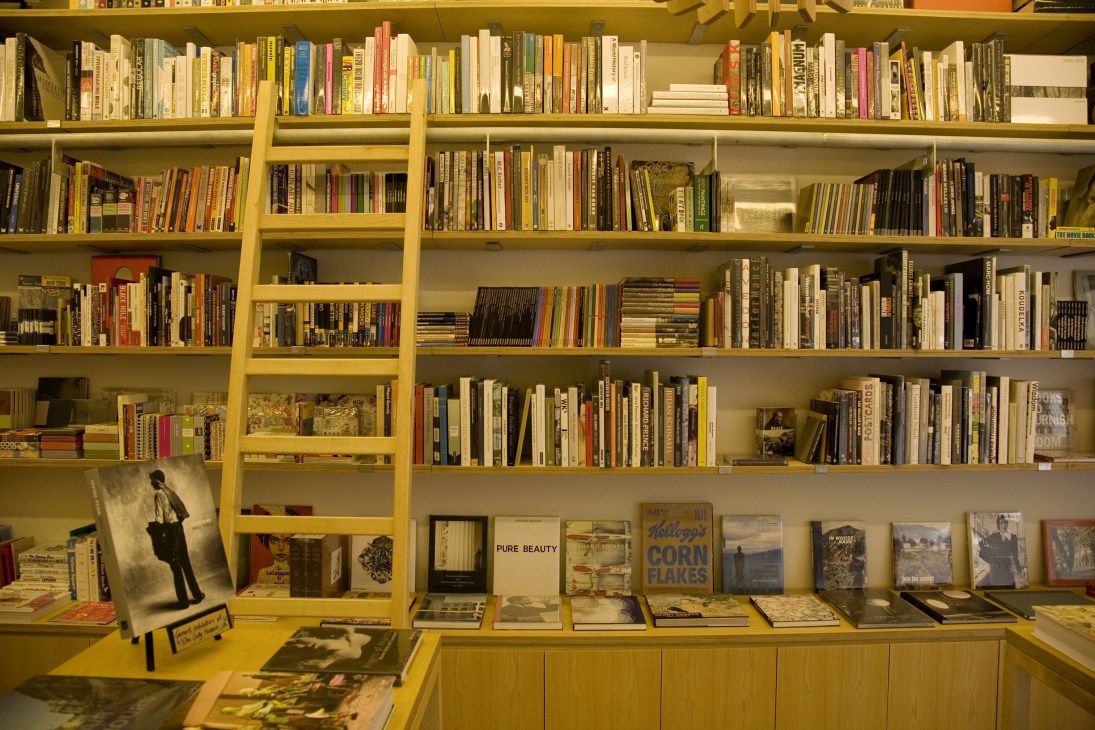 Yellow shelving displaying books, magazines, and art books at Papercup bookstore in Beirut.