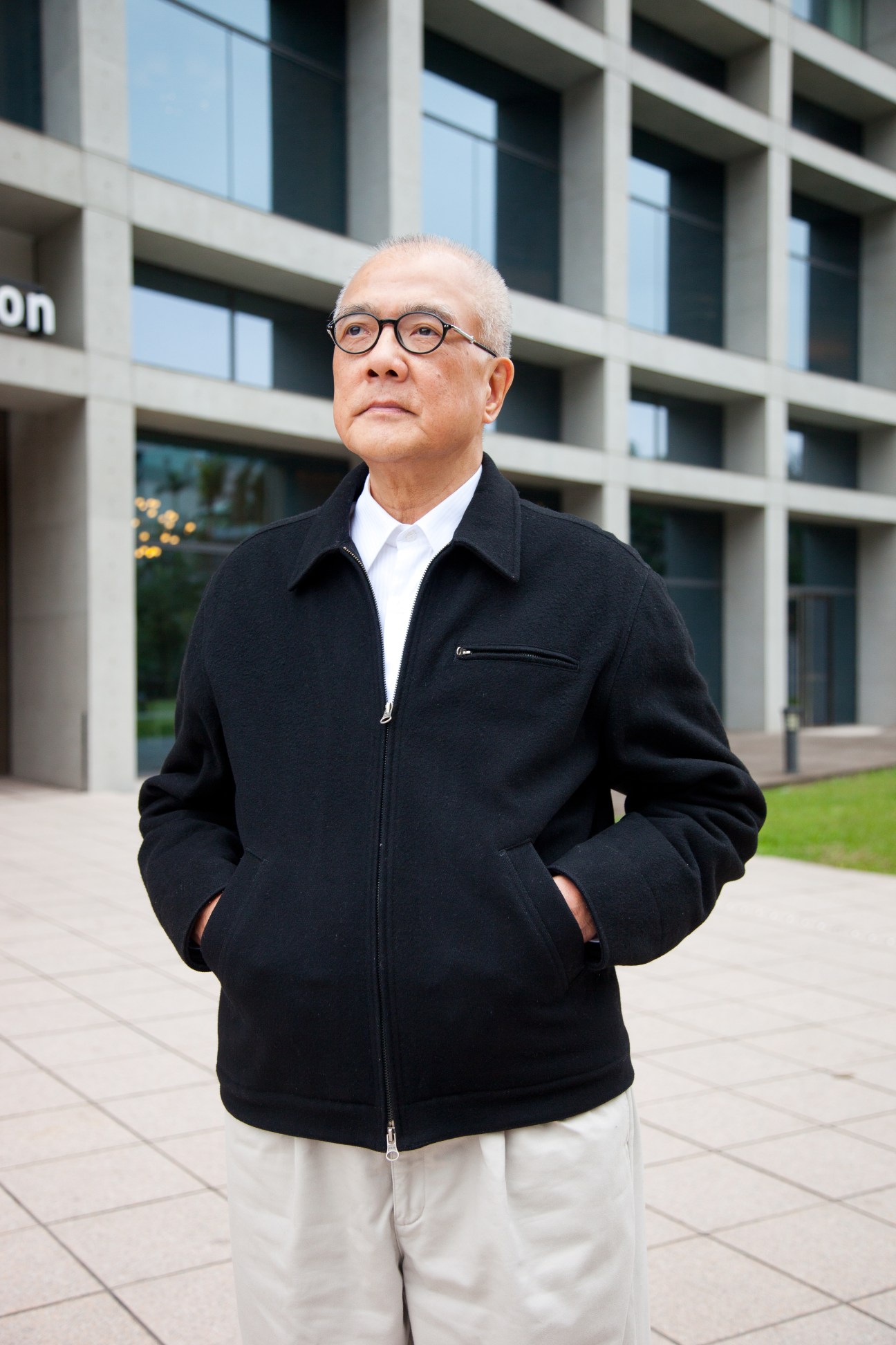 Robert Wu, founder of Eslite booksellers, standing in front of a modern building wearing glasses and a black jacket.