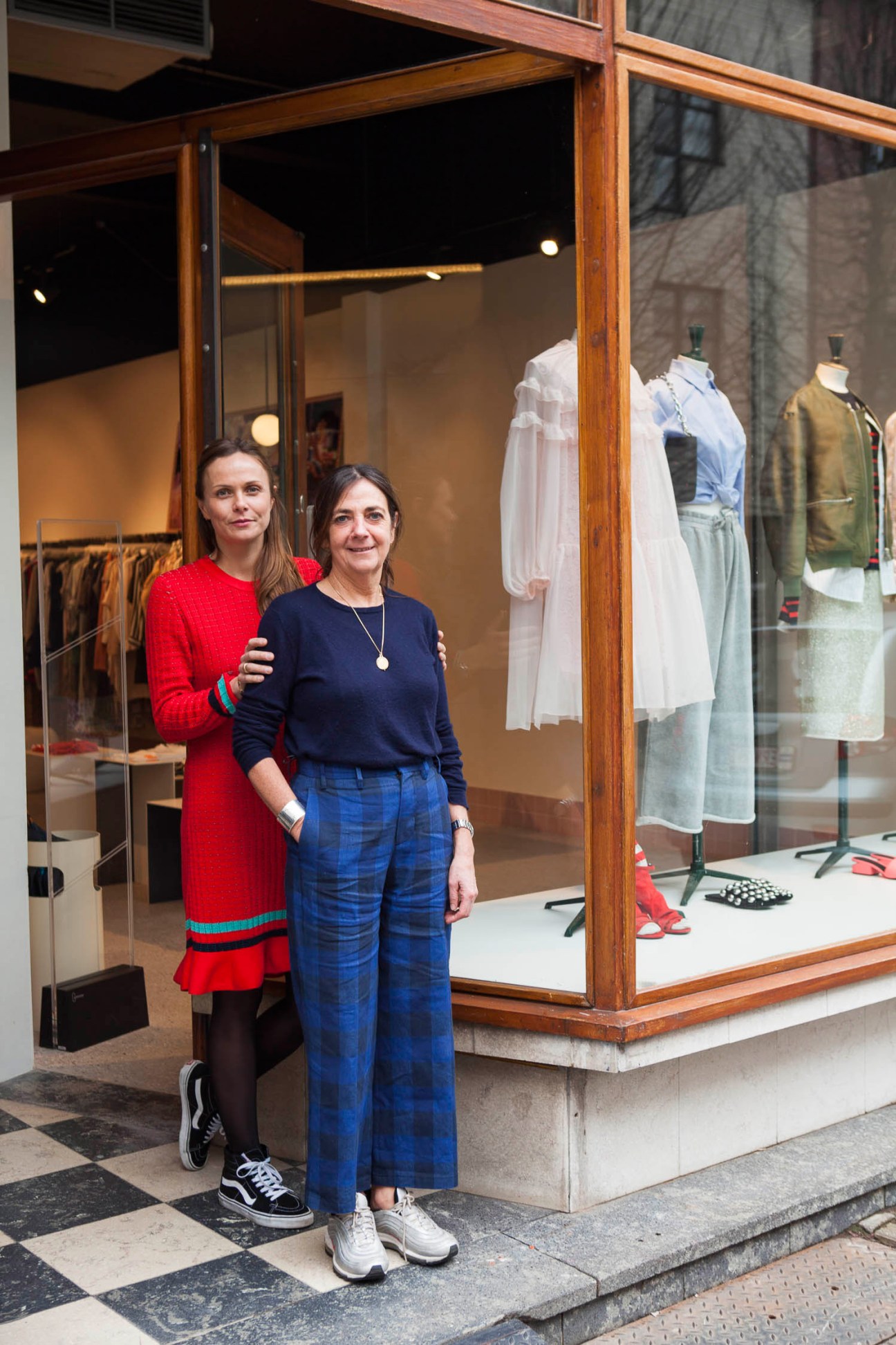 Two women standing outside Step by Step boutique in Antwerp with fashion displays in window