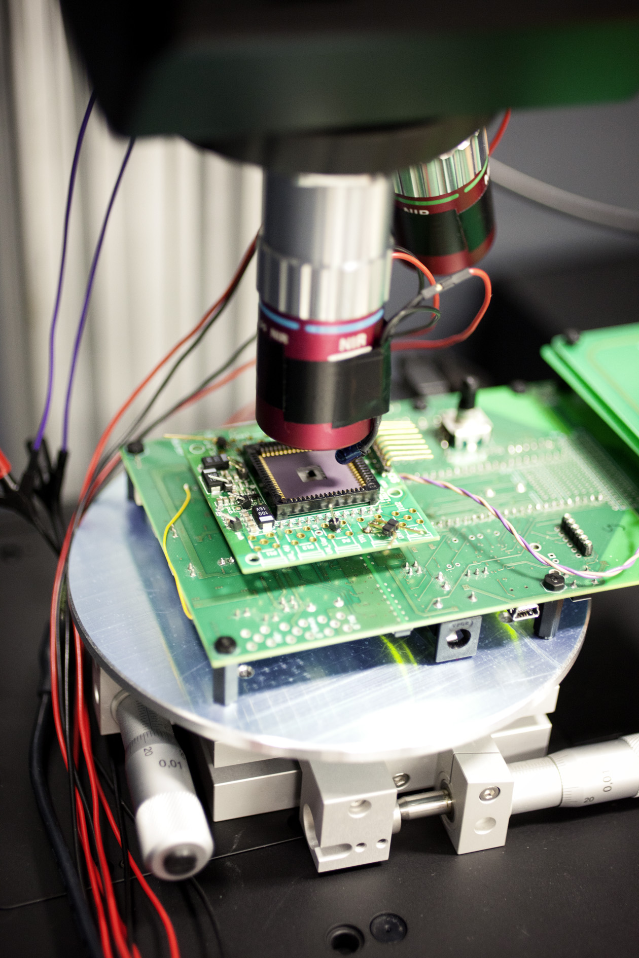 Close-up of NXP semiconductor laboratory setup with green circuit board and electronic testing equipment.