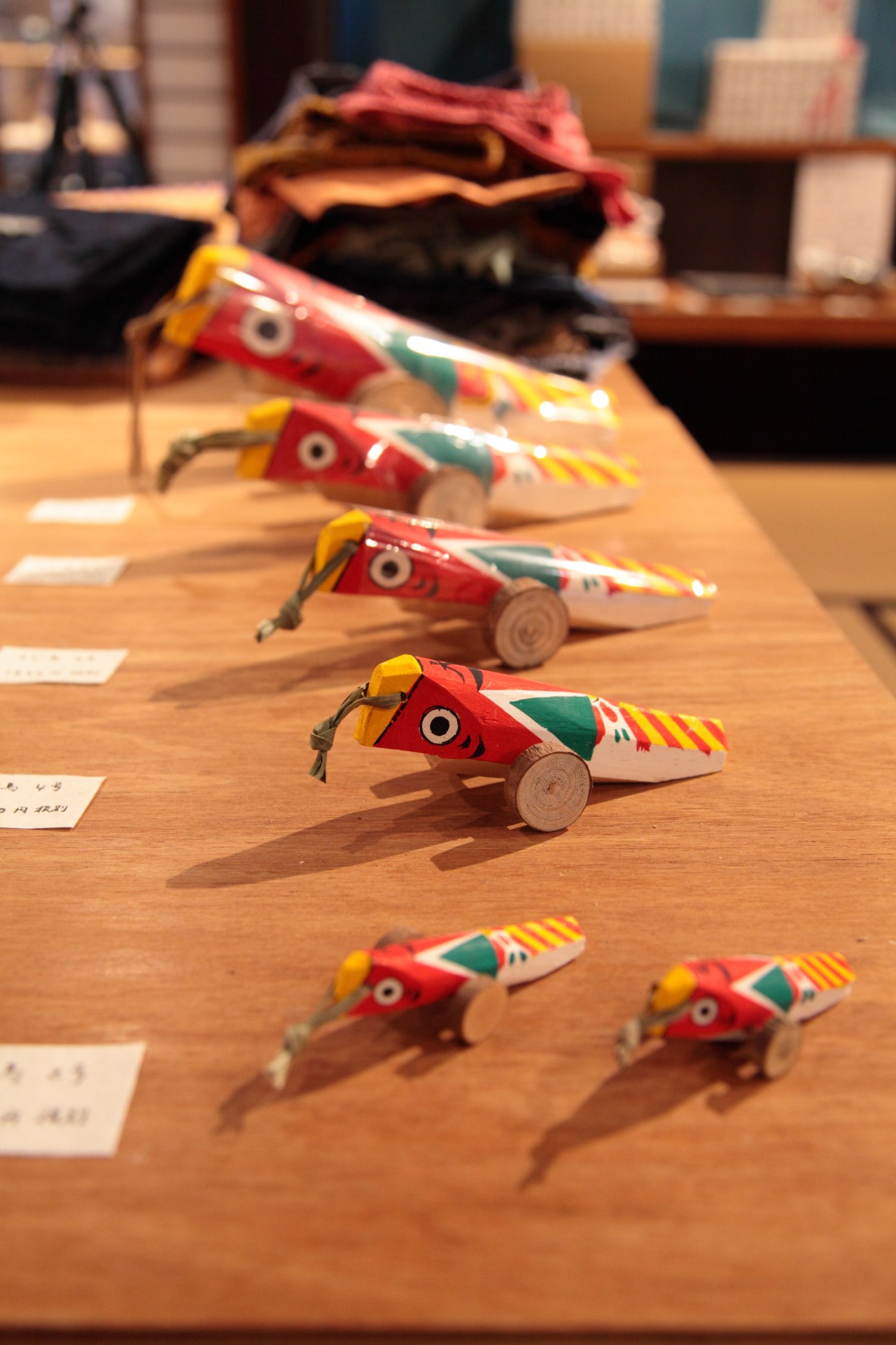 Colorful wooden toy fish arranged in a row on a wooden surface.