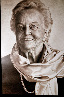 Portrait of an older woman wearing a pearl necklace and light-colored scarf.