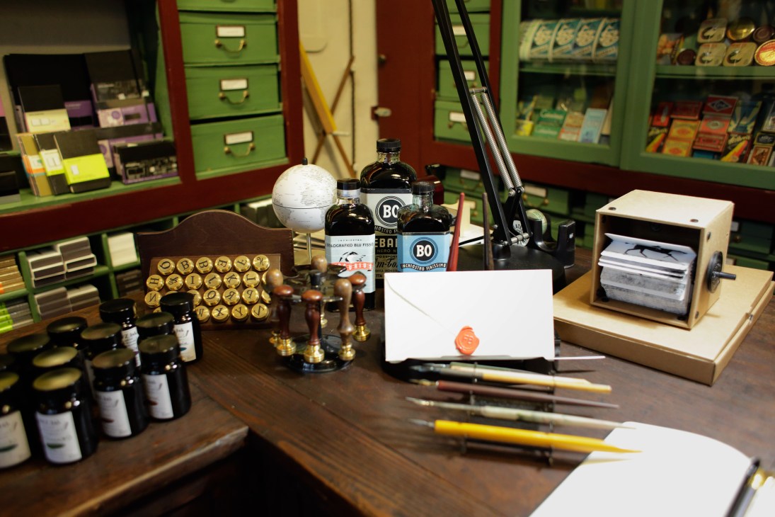 Display of vintage stationery items including ink bottles, pens, letters, and brass fixtures at Fratelli Bonvini shop.