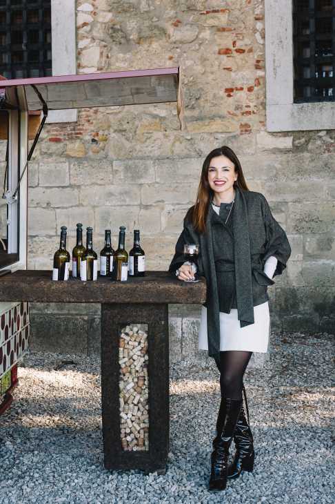 Barbara Vidal standing at her Wine With a View mobile bar setup with Portuguese wine bottles displayed.