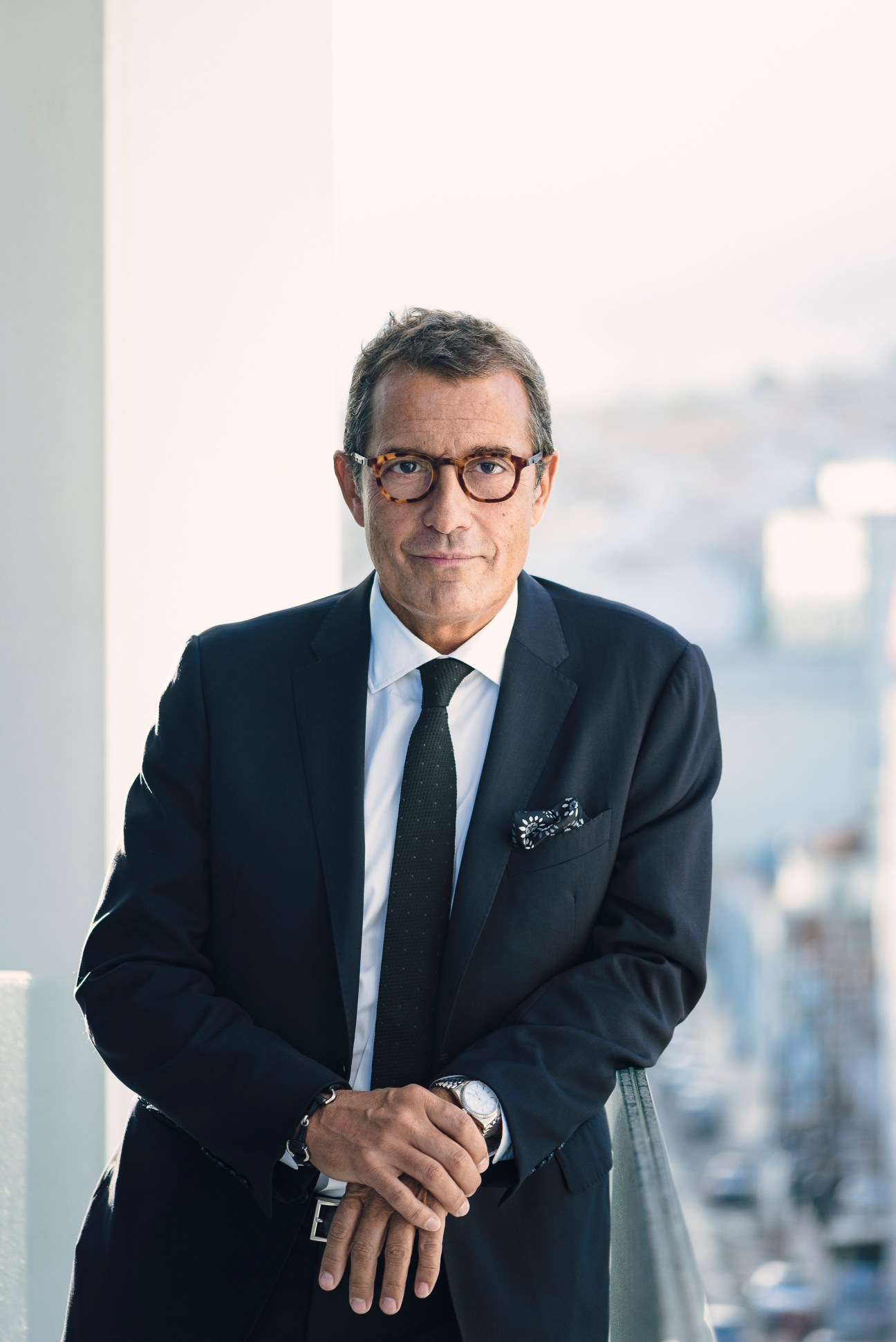 Portrait of António Mexia, EDP CEO, wearing glasses and dark suit against a cityscape background.