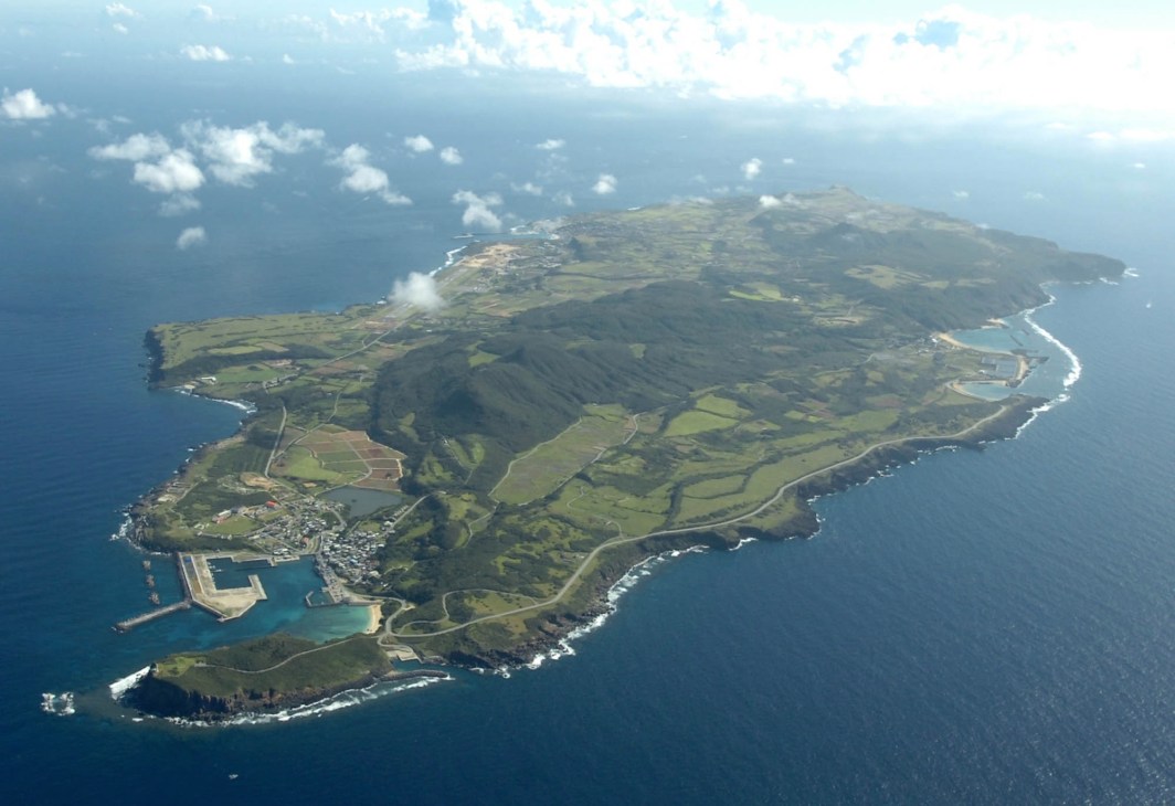 Aerial view of Yonaguni Island surrounded by blue ocean waters with green fields and coastal settlements visible.
