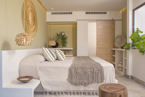 Modern hotel bedroom with neutral tones, woven wall art, and natural textures