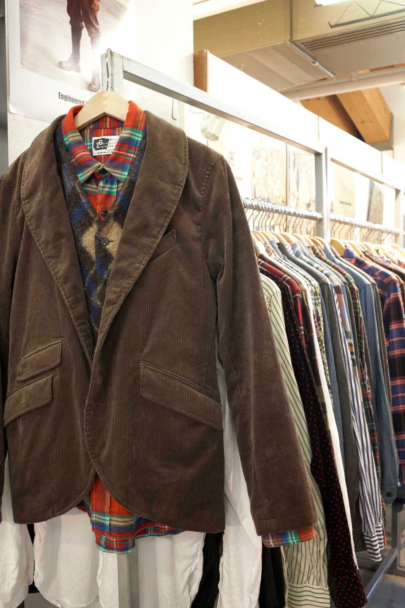 Brown corduroy blazer with tartan shirt displayed on hanger at Pitti menswear show exhibition.