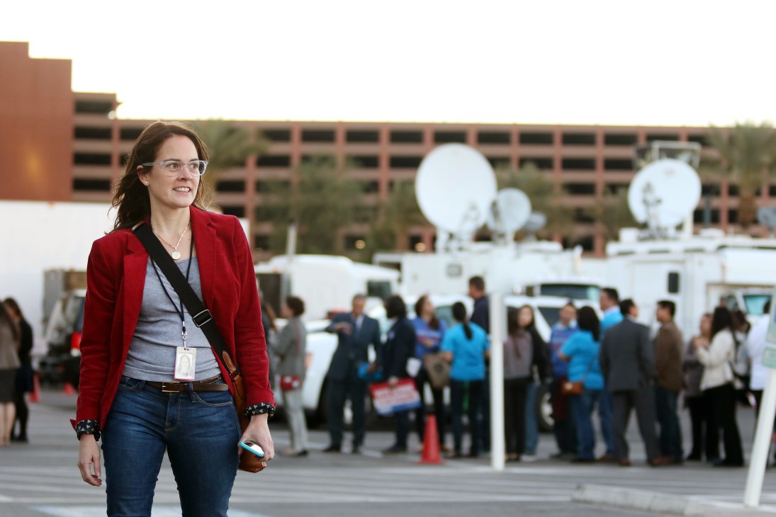Annie Linskey, political reporter for The Boston Globe, wearing a red blazer and press credentials at a campaign event.