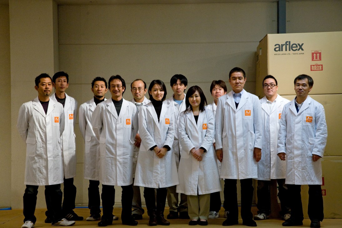 Arflex Japan team members wearing white lab coats standing in a line at their Asahikawa production facility.