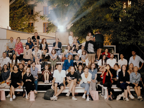 Large group of people posing together on outdoor steps at night in an urban setting.