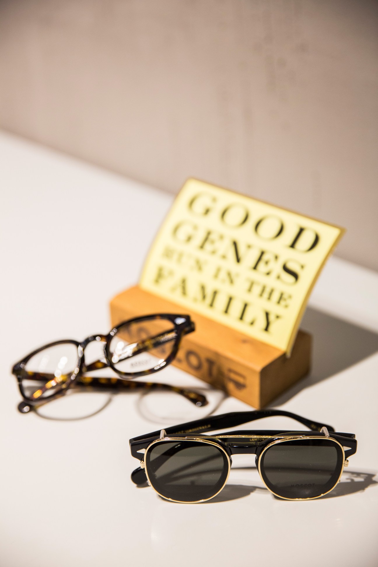 Two pairs of eyeglasses and a yellow branded box displayed on a white surface.