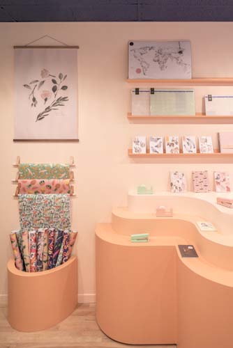 In Bed retail store interior with peach curved furniture, wooden shelving, and displayed textiles.