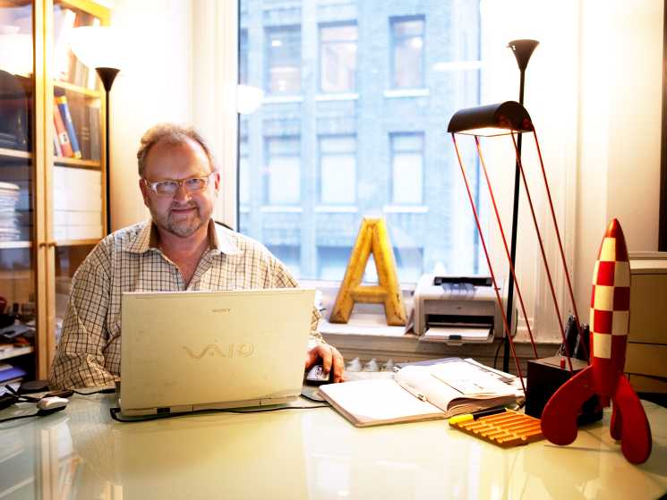 Mark Batty sits at his desk in his Manhattan office surrounded by colorful design objects and books.