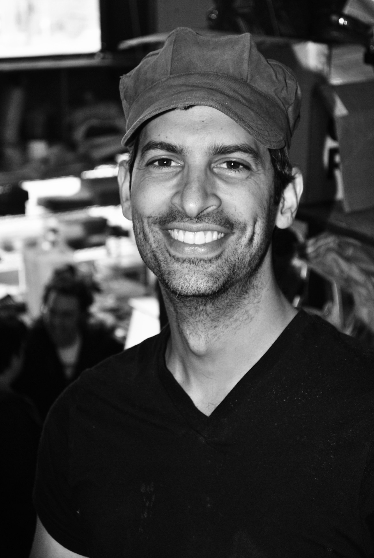 Black and white portrait of a man wearing a cap smiling at the camera.